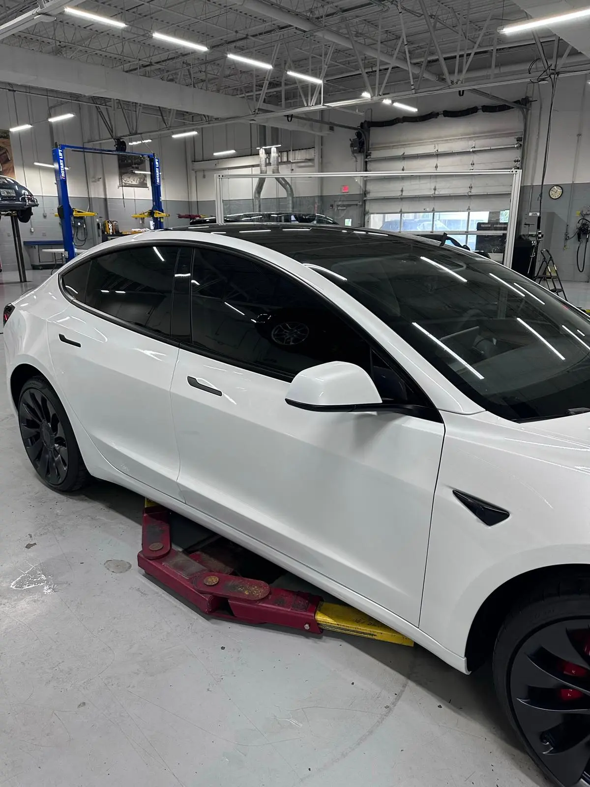 White luxury sedan on lift in professional automotive facility